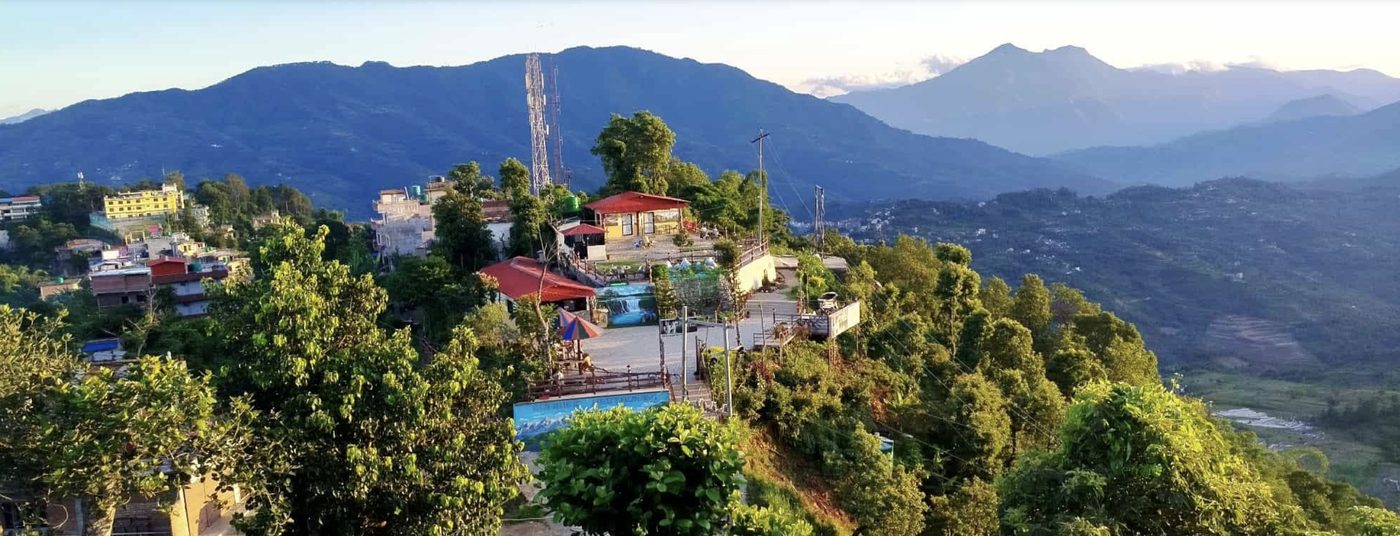 Sunrise Cafe on the ridge above Gorkha at golden hour, red-roofed terraces with the Himalayan foothills behind